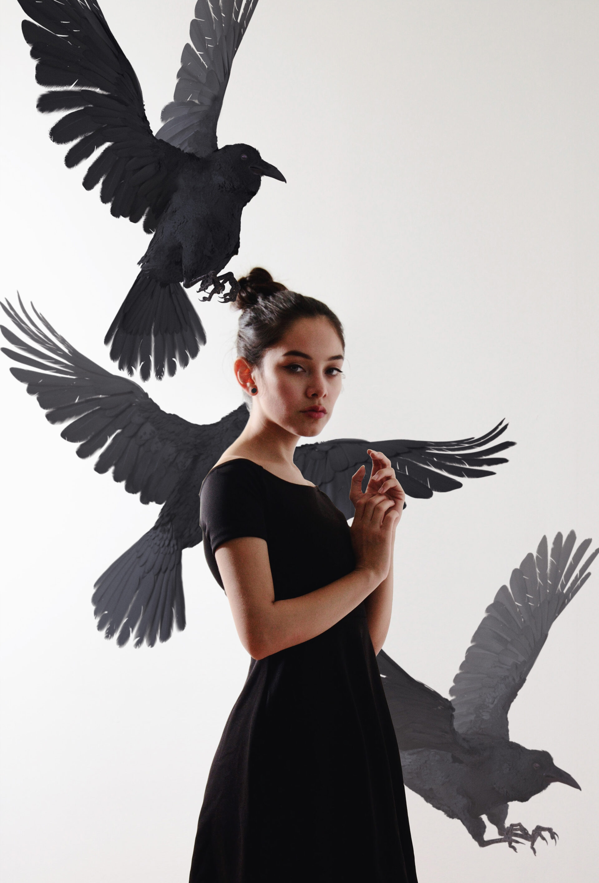 Maria Fernanda in a black dress stands against a white background with three black birds in various stages of flight around her.